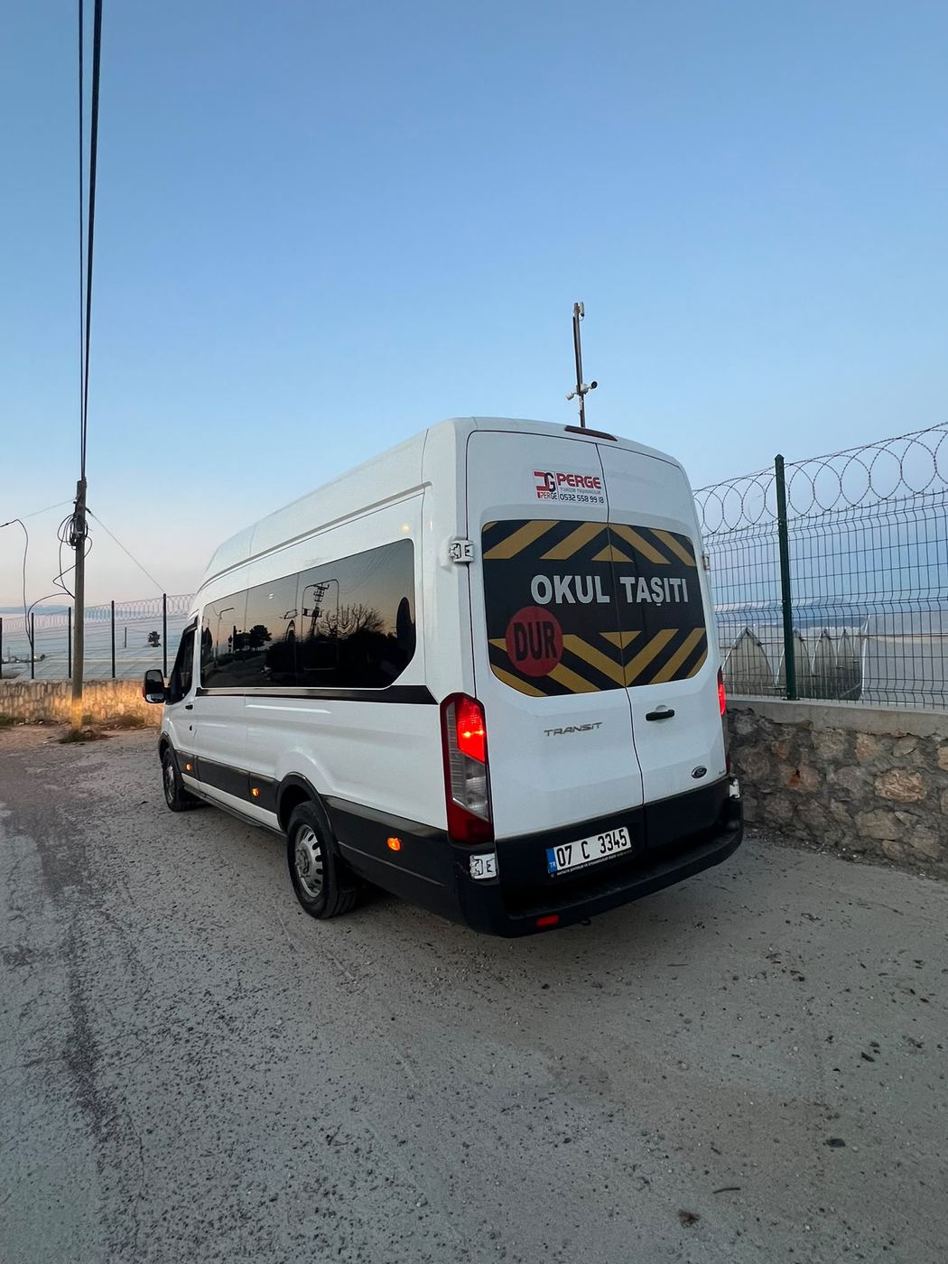 Okul taşıtı yazılı beyaz Ford Transit, kıyı yolunda.