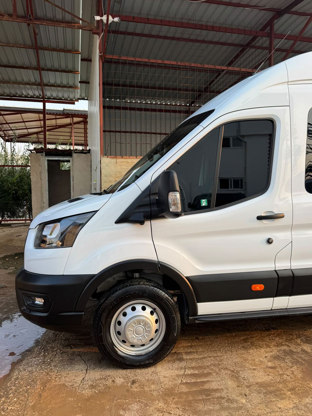 Beyaz Ford Transit minibüsün yan görünümü.